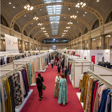 Exhibition hall showcasing clothing designs, grand venue with multiple booths and visitors