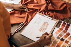 Fashion designer sketching clothing ideas on fabric samples