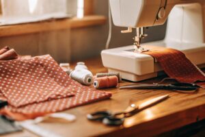 Sewing machine with fabric and tailoring tools on a wooden table