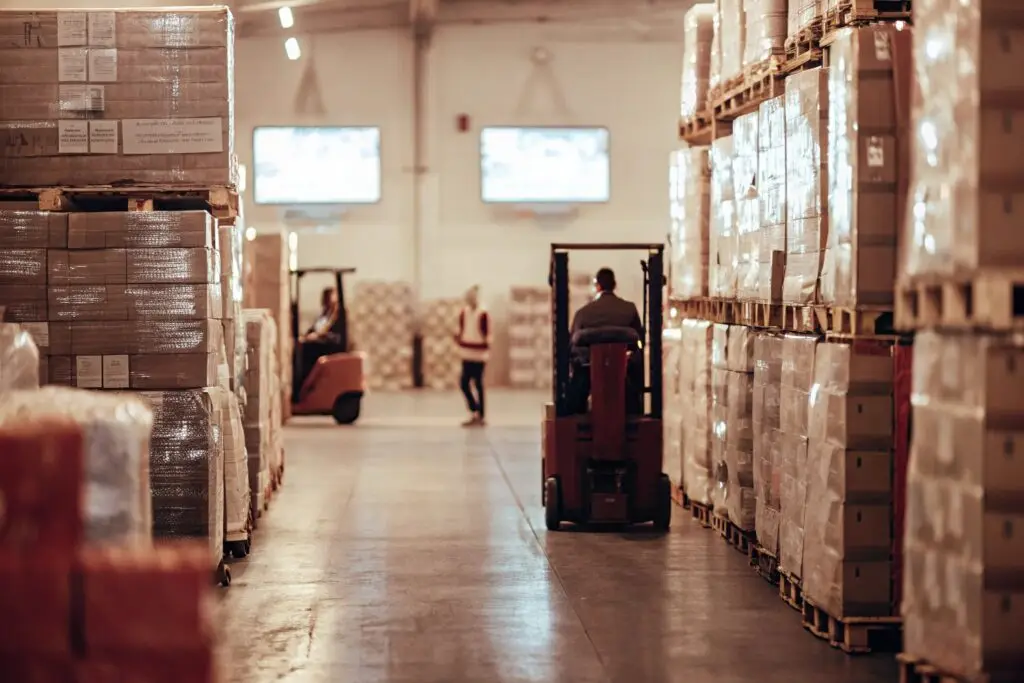 Massive logistics warehouse with forklifts moving packed shipments