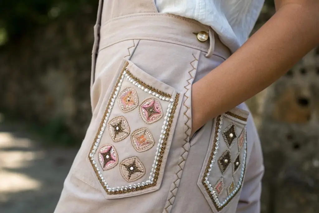 Decorative pockets with intricate embroidery and embellishments on beige trousers