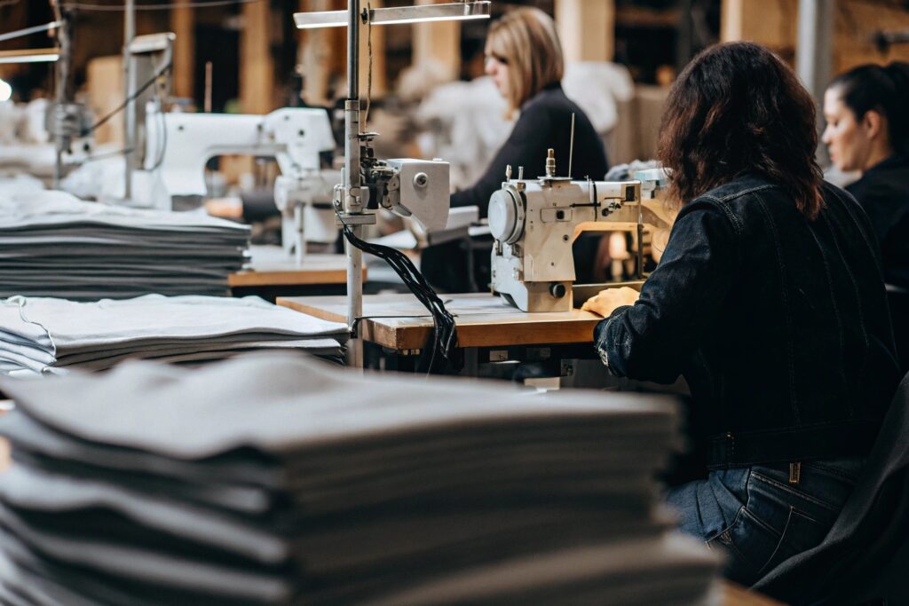 High-quality clothing production line with skilled workers, sewing machines, and fabric stacks