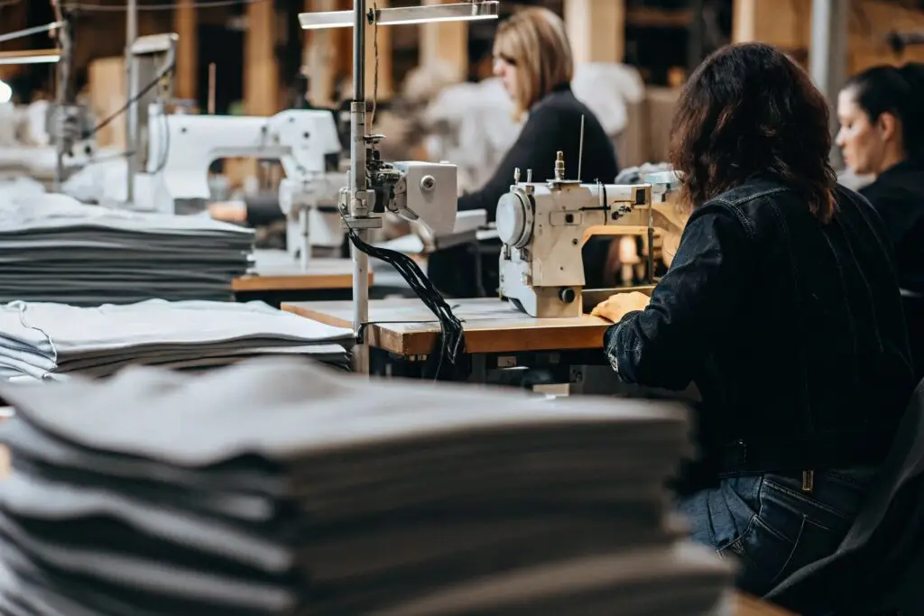 High-quality clothing production line with skilled workers, sewing machines, and fabric stacks