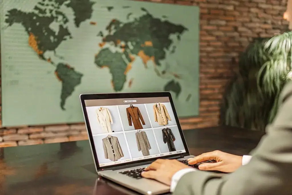 A business professional browsing an online B2B marketplace for apparel, selecting tailored garments against a backdrop of a world map, symbolizing global sourcing and trade.