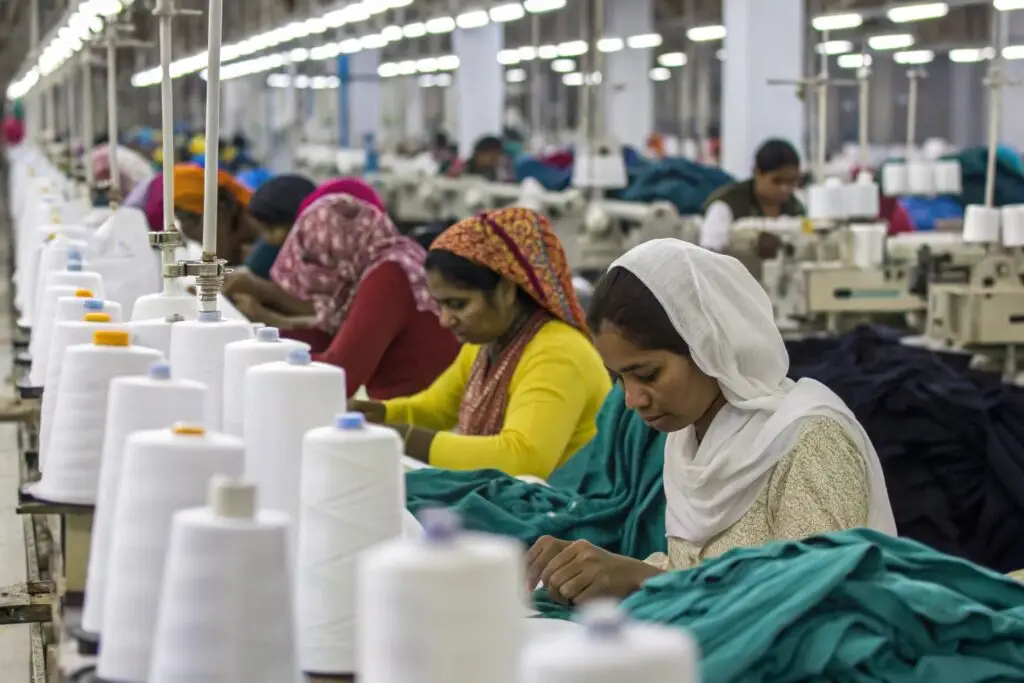 Workers sewing garments in a busy factory line