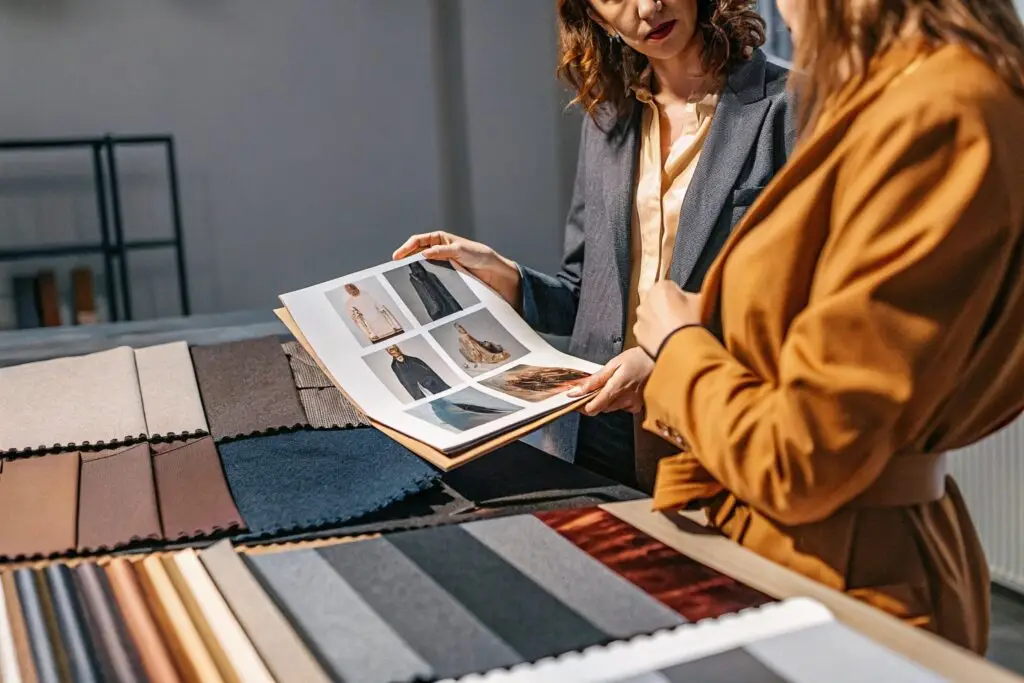 A fashion designer showcasing a portfolio filled with clothing sketches and fabric samples during a professional consultation.