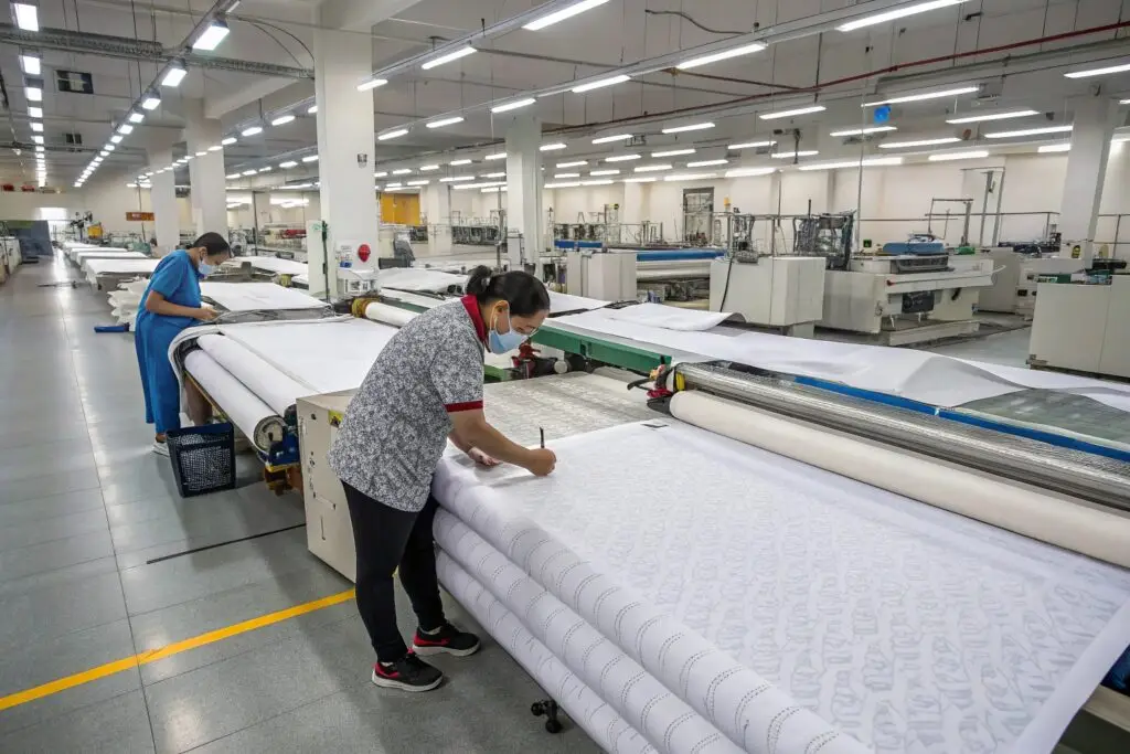 Workers inspecting and marking fabric in a textile manufacturing facility