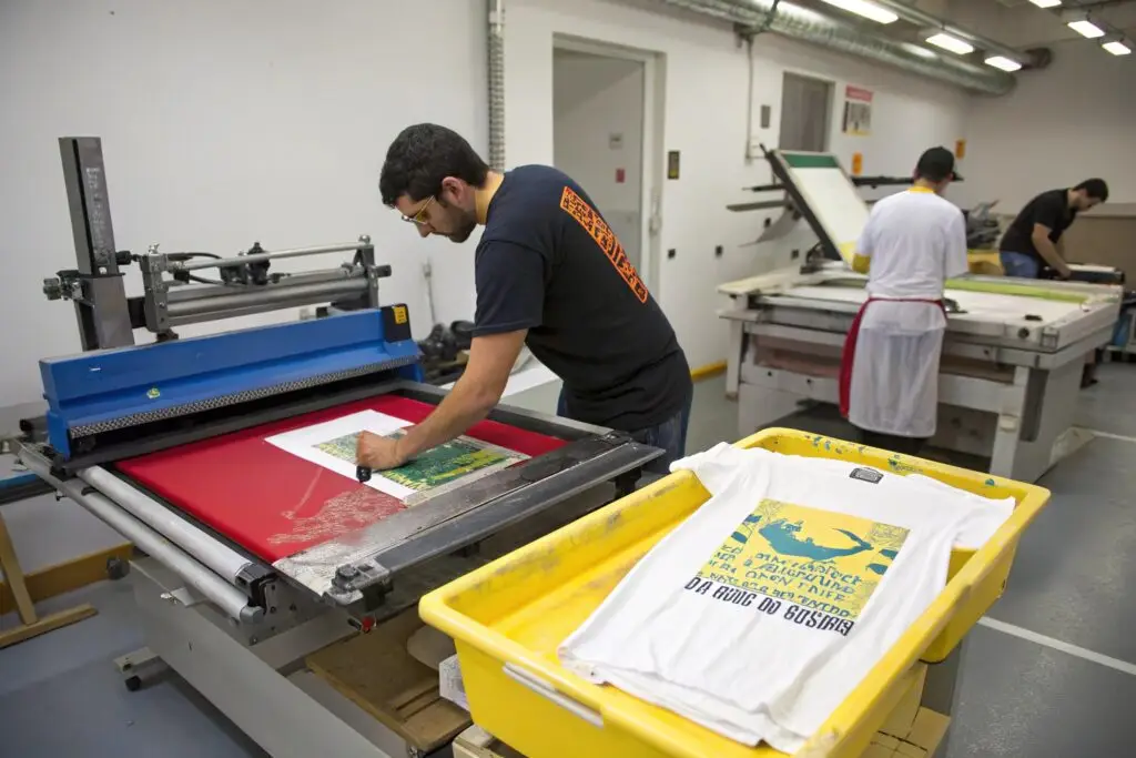 Workers operating screen printing machines in a workshop
