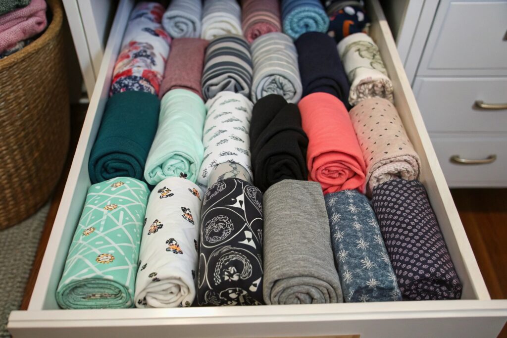 Neatly organized drawer with colorful rolled fabrics in various patterns and textures