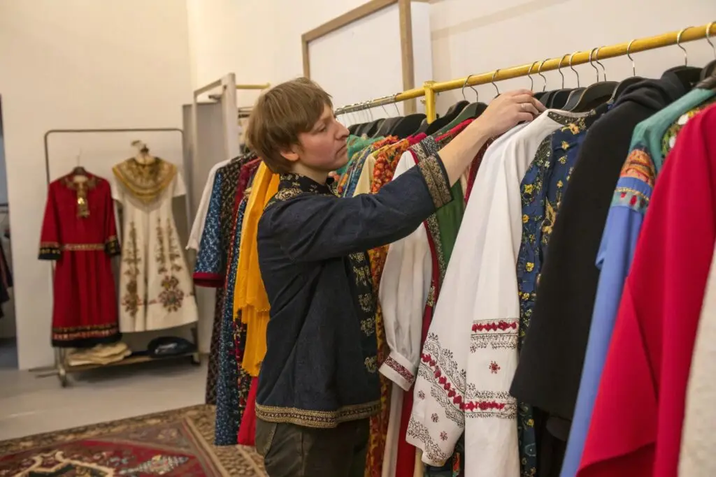 person browsing traditional or embroidered clothing on display rack