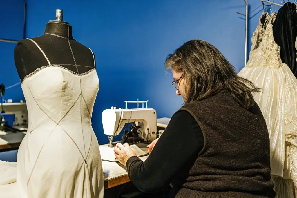 A seamstress in a fashion studio sewing a custom-made wedding gown.