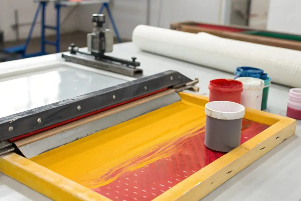 Close-up of essential screen printing materials, including ink and squeegee on a screen frame