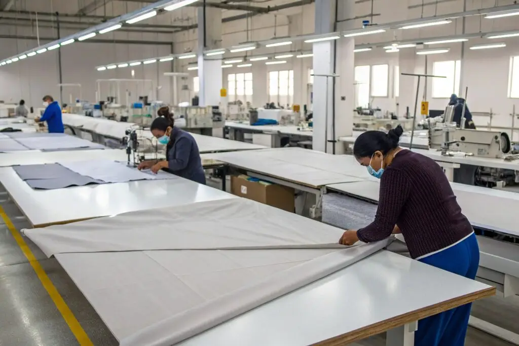 Workers preparing fabric in a large garment manufacturing facility