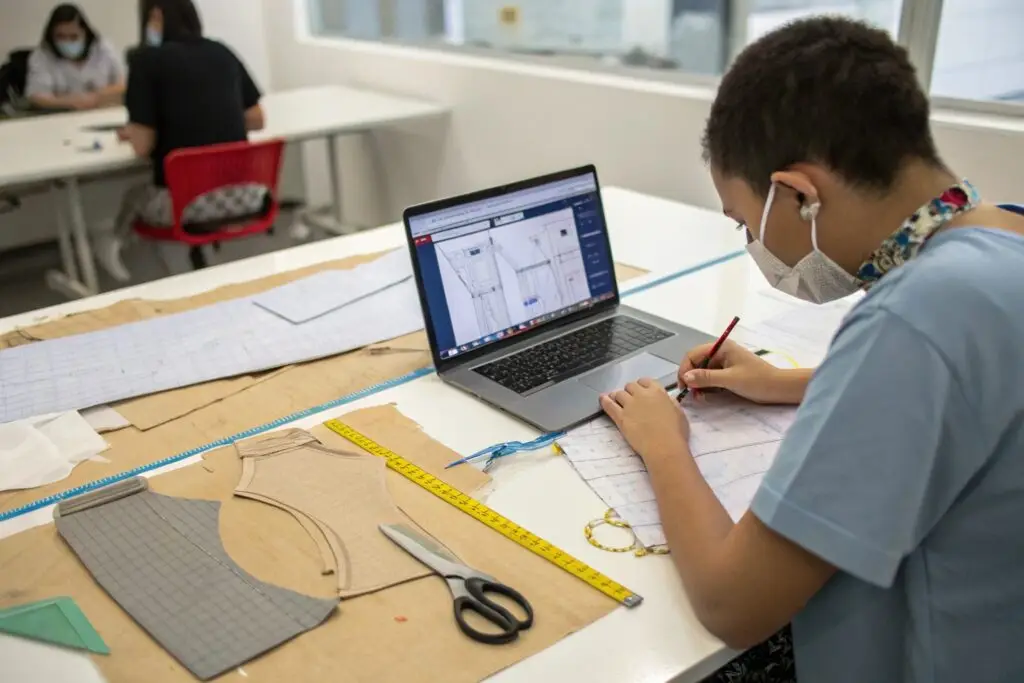 Student working on fashion patterns and designs at a desk