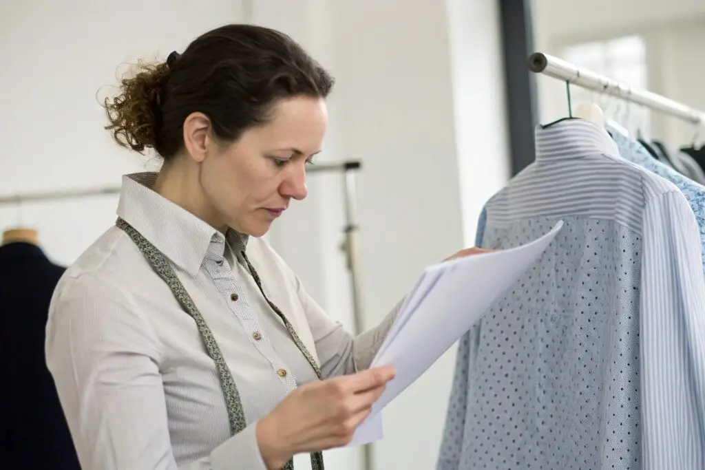 Tech pack designer reviewing garment details and sketches in a clothing studio