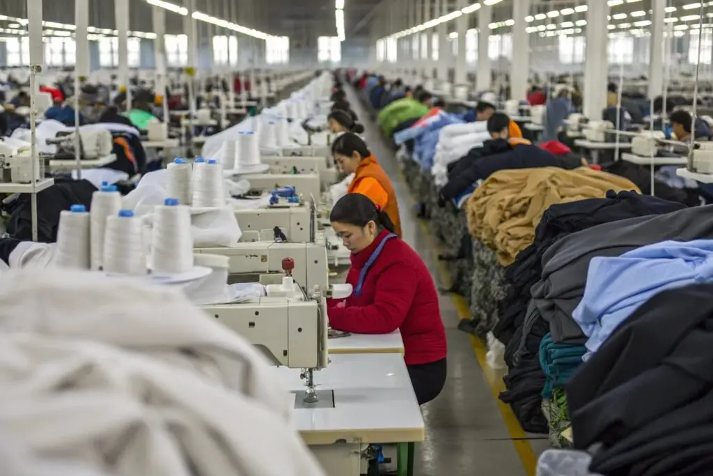 Large clothing manufacturing warehouse with workers sewing garments