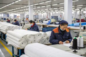 Workers in a garment factory handling fabric rolls