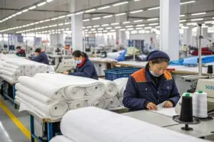 Workers in a garment factory handling fabric rolls