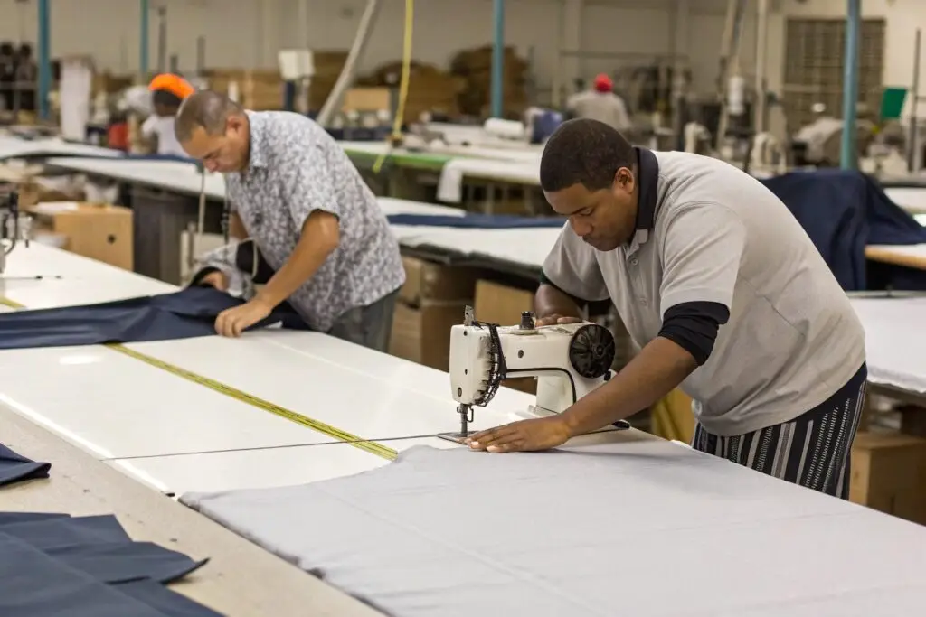 Garment workers sewing and cutting fabric at tables