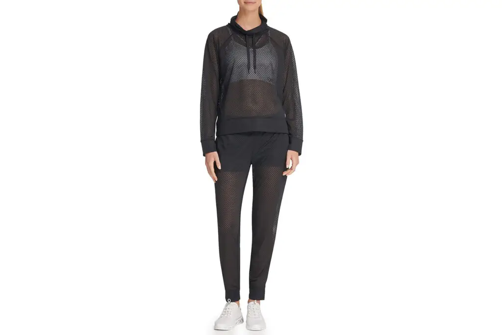 Model wearing a black mesh tracksuit with white sneakers