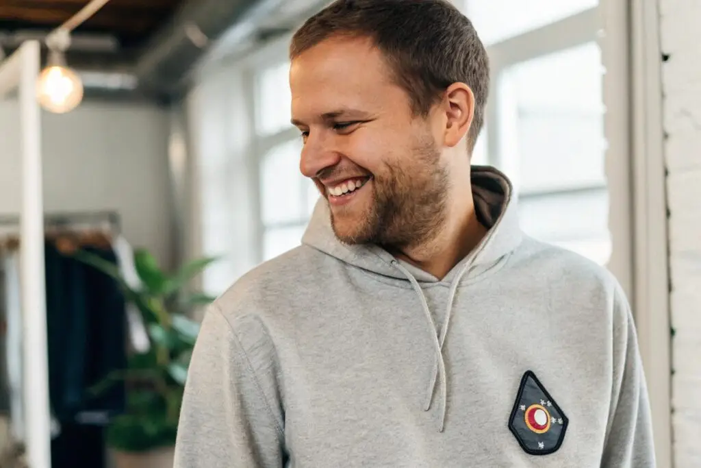 A customer smiling while wearing a sweatshirt with a patch