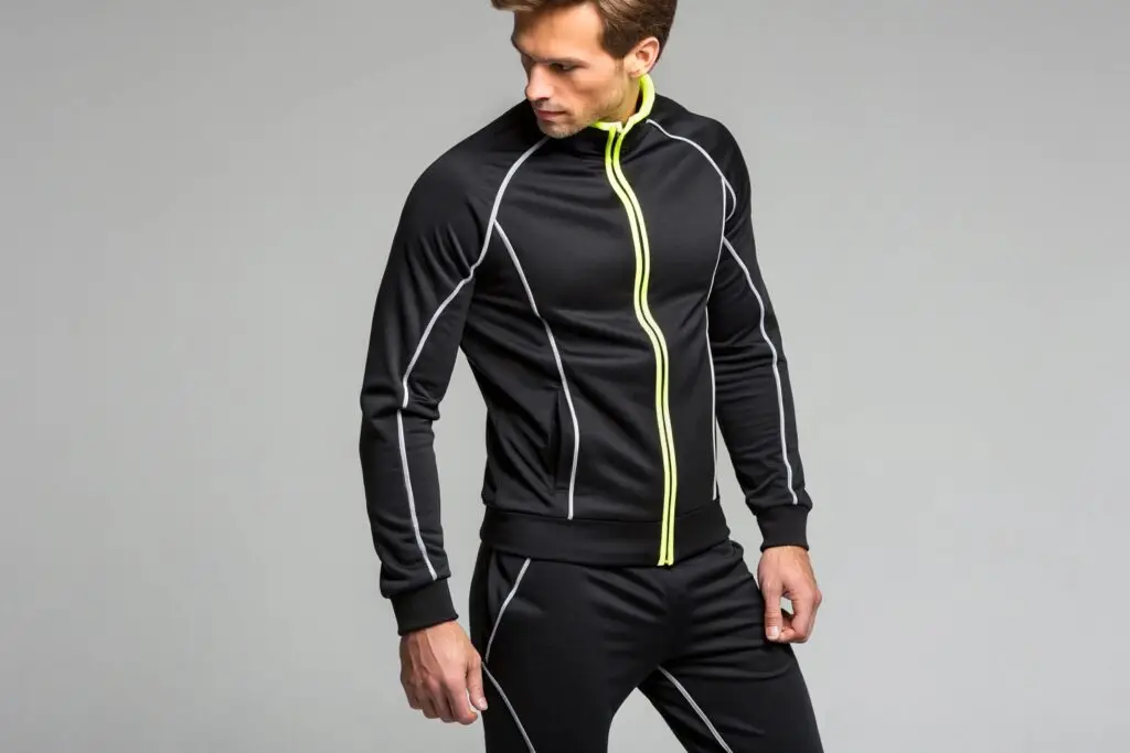 Male fitness model wearing a modern black neoprene tracksuit with neon yellow details