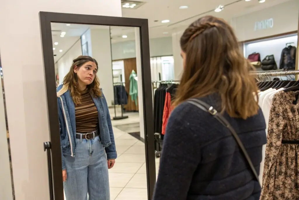 Shopper looking disappointed at poor garment fit in mirror