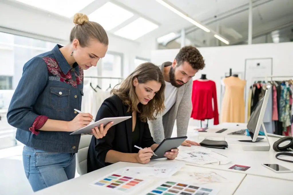 Fashion designers sketching and reviewing concepts on tablets