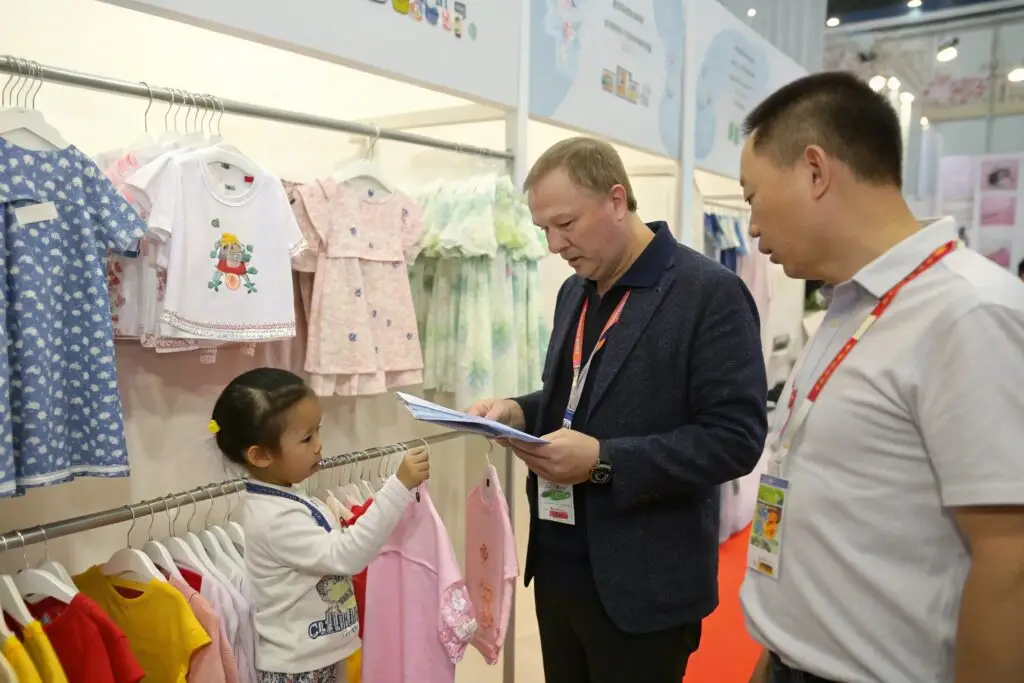 Buyer inspecting kidswear collection at colorful trade booth
