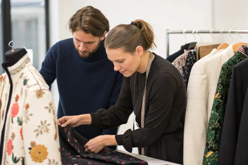 Fashion brand designers reviewing garment designs and fabric samples in a design studio