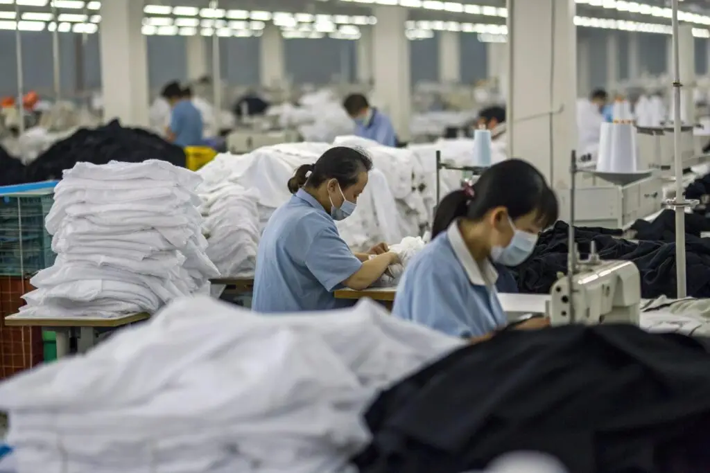 Chinese garment workers sewing and inspecting clothes in busy factory