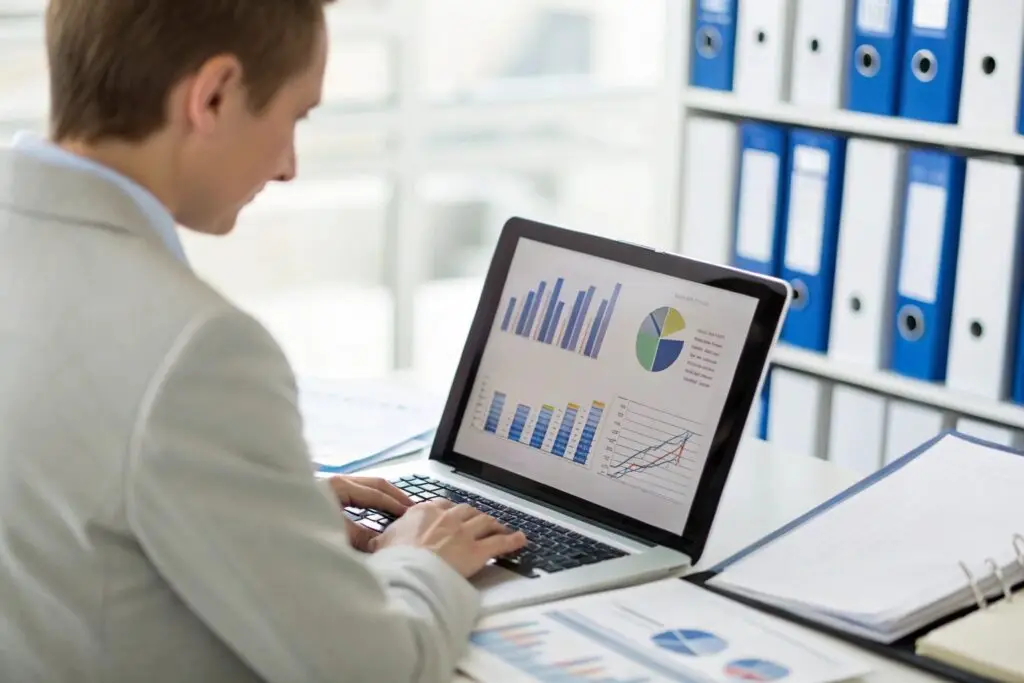Business analyst reviewing graphs and charts on laptop screen