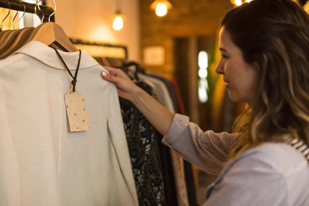 woman checking garment label on clothing rack in warm boutique setting